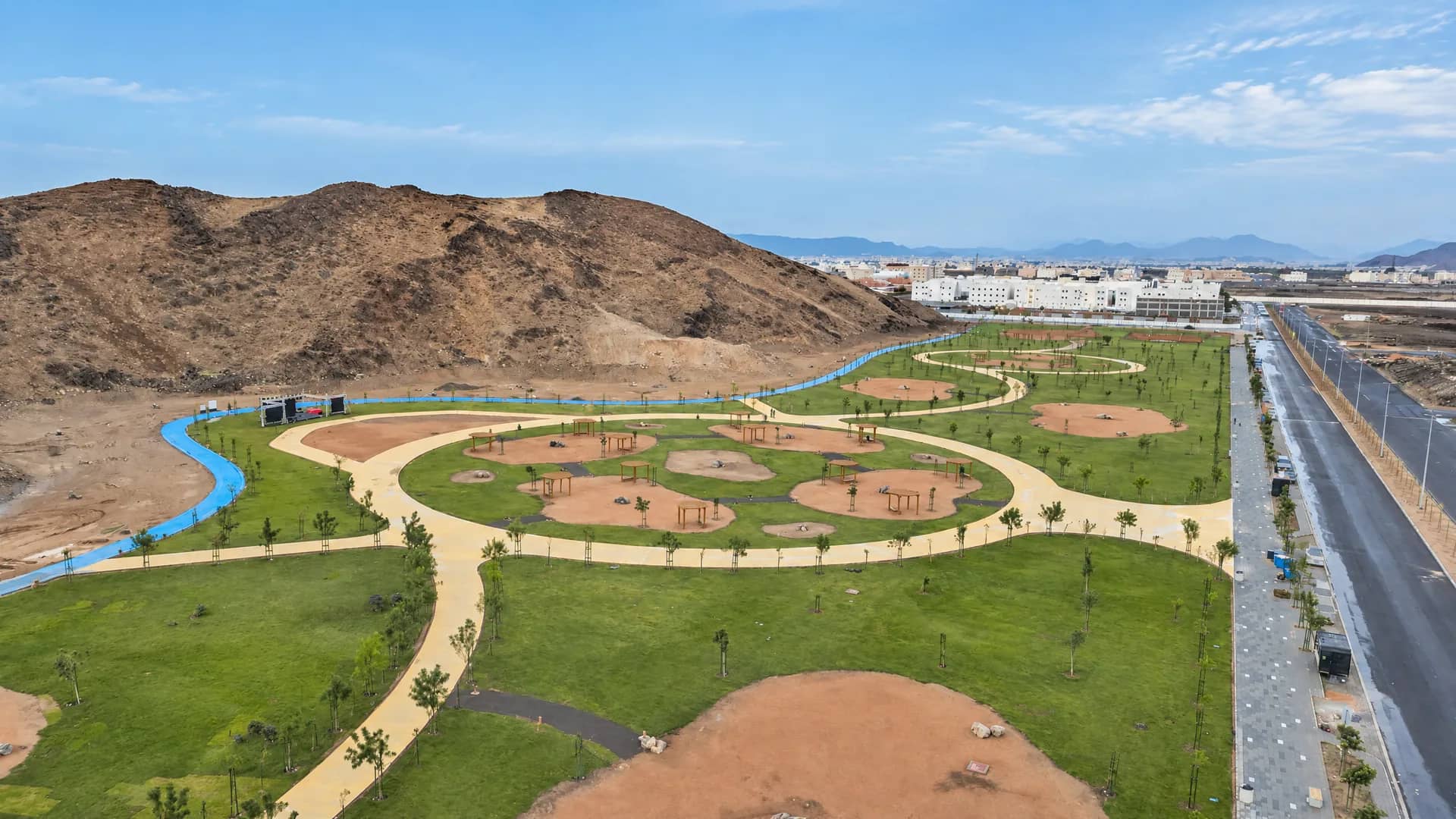 مشهد جوي لحديقة الجبل ومساراتها ومساحاتها الخضراء مع الجبل والحي المحيط