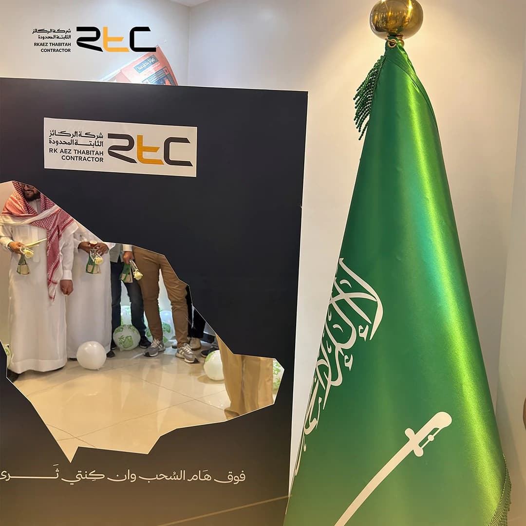 ركن الاحتفال بخلفية الشركة وخريطة المملكة والعلم السعودي، ويظهر الحضور عبر فتحة الخريطة حاملين الورود والهدايا