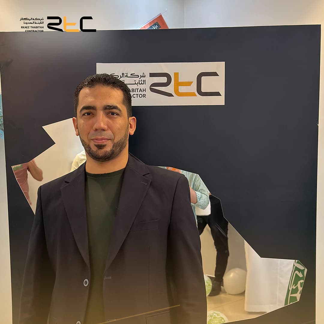 أحد الحضور بسترة داكنة أمام خلفية الاحتفال التي تحمل هوية الشركة وخريطة المملكة