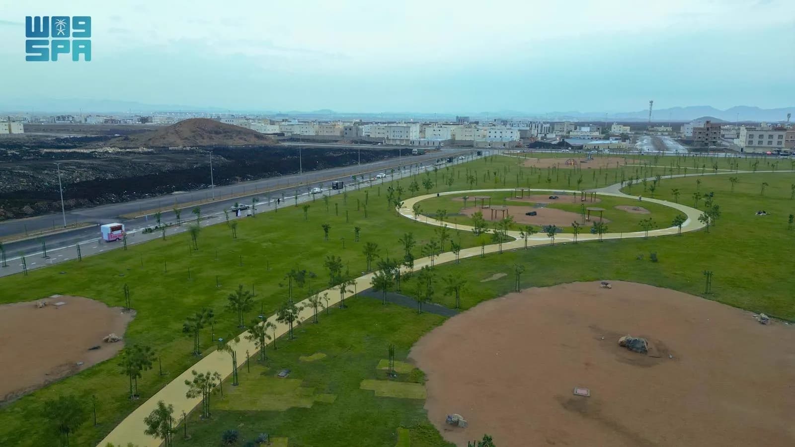 منظر جوي للمسطحات الخضراء والمسارات الدائرية والطريق المجاور