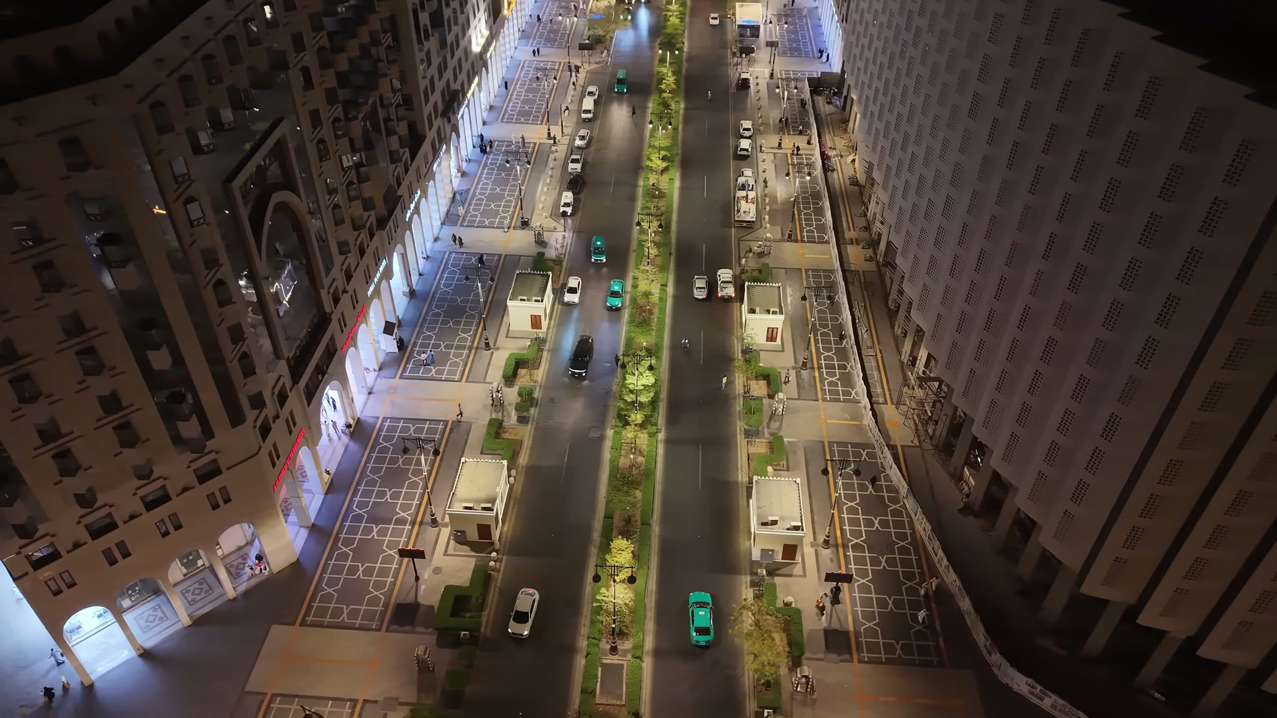Aerial night view along the Central Area corridor in Madinah showing lighting along the roadway and pedestrian routes