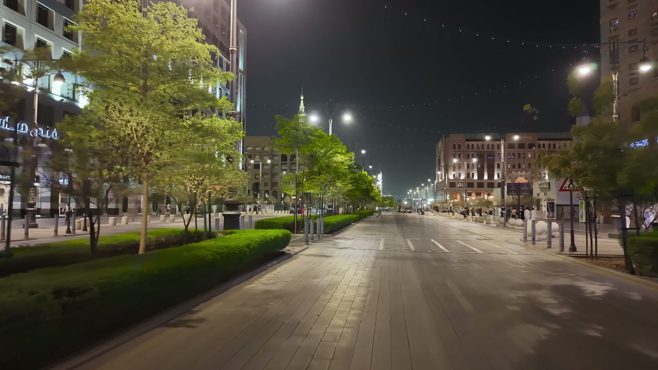 Street-level night view of the Central Area corridor in Madinah showing lighting columns and pedestrian routes