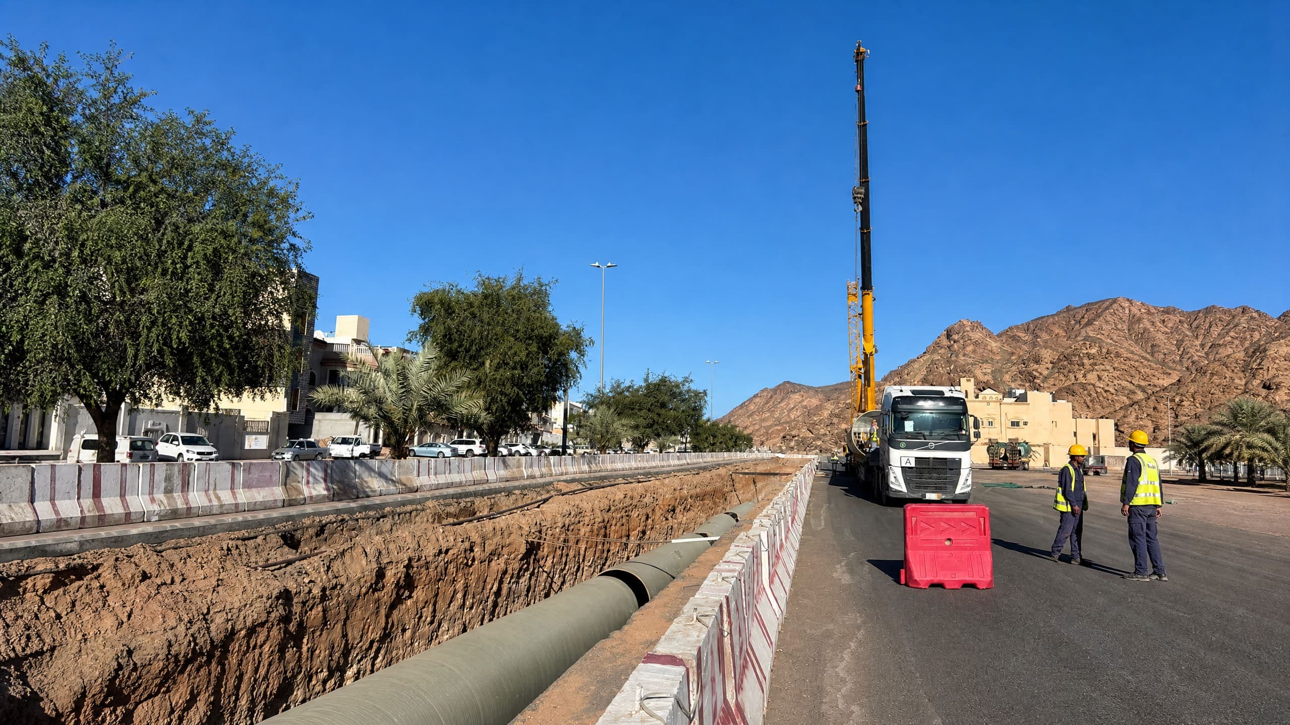 خط تصريف ممدد داخل الخندق ورافعة وشاحنة ضمن منطقة العمل المحاذية للطريق في مشروع حمراء الأسد